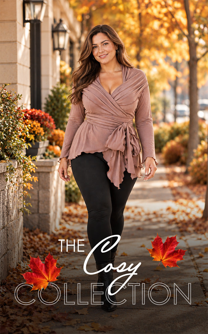 Woman modeling a dusty rose wrap top with a draped neckline, long sleeves, and a tie waist, paired with black leggings on an autumn sidewalk. Golden fall foliage, pumpkins, and red maple leaves frame the scene. Promotional text reads “The Cozy Collection.”