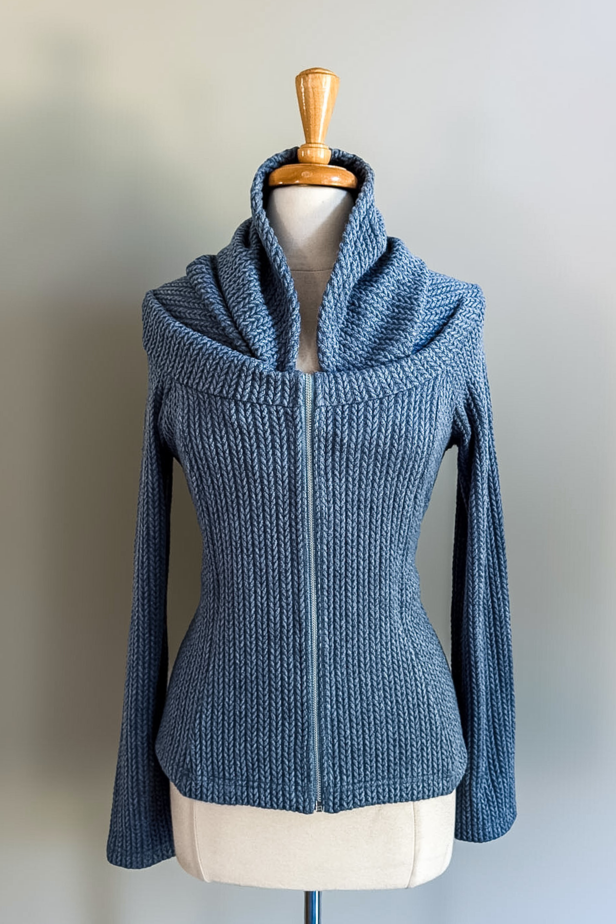 Blue knitted convertible hoodie on a mannequin against a plain background