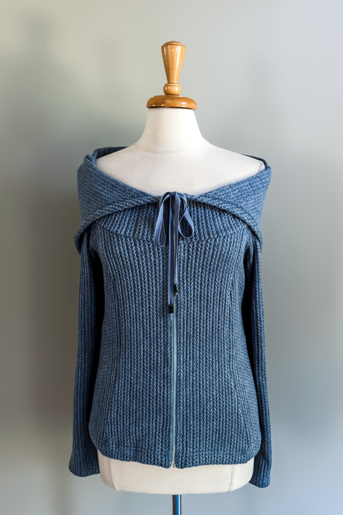 Blue knitted convertible hoodie on a mannequin against a plain background
