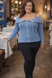 A woman standing and wearing a blue knitted convertible hoodie travel outfit video